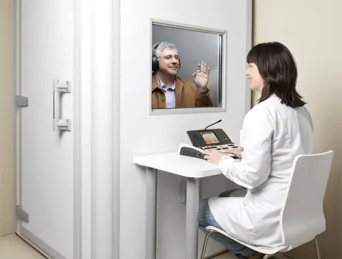 Paciente realizando exame de audiometria em cabine acústica