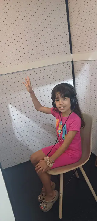 Criança realizando audiometria em cabine acústica